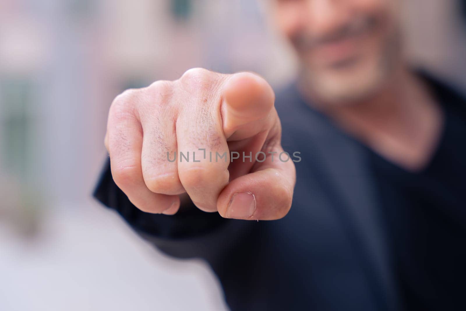 Unrecognizable middle adult pointing finger to front of logo. Smiling man pointing finger towards camera.