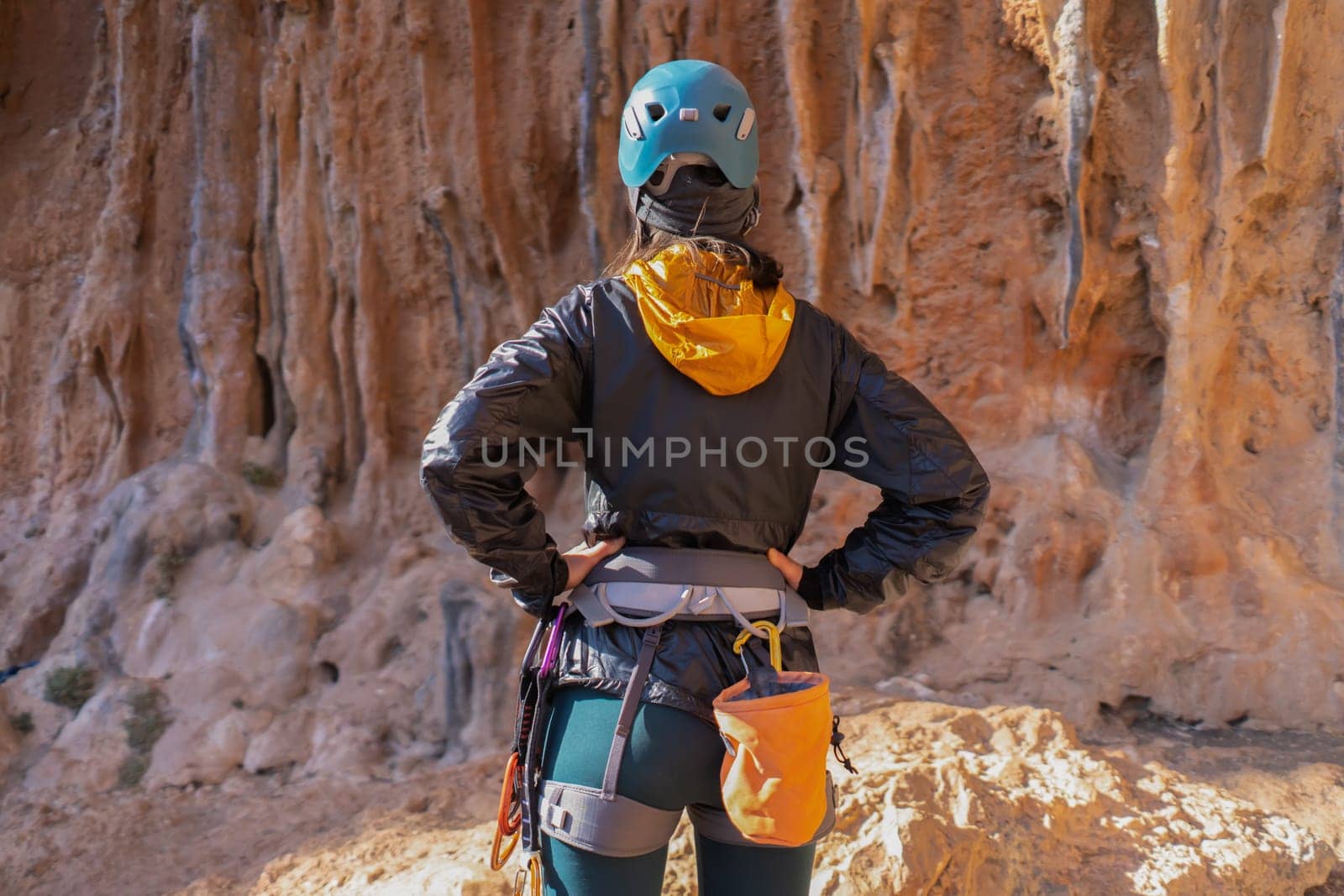 A young girl is engaged in active sports, rock climbing and mountaineering. A woman looks at a beautiful red rock and takes magnesia in her hand, getting ready for training and climbing.