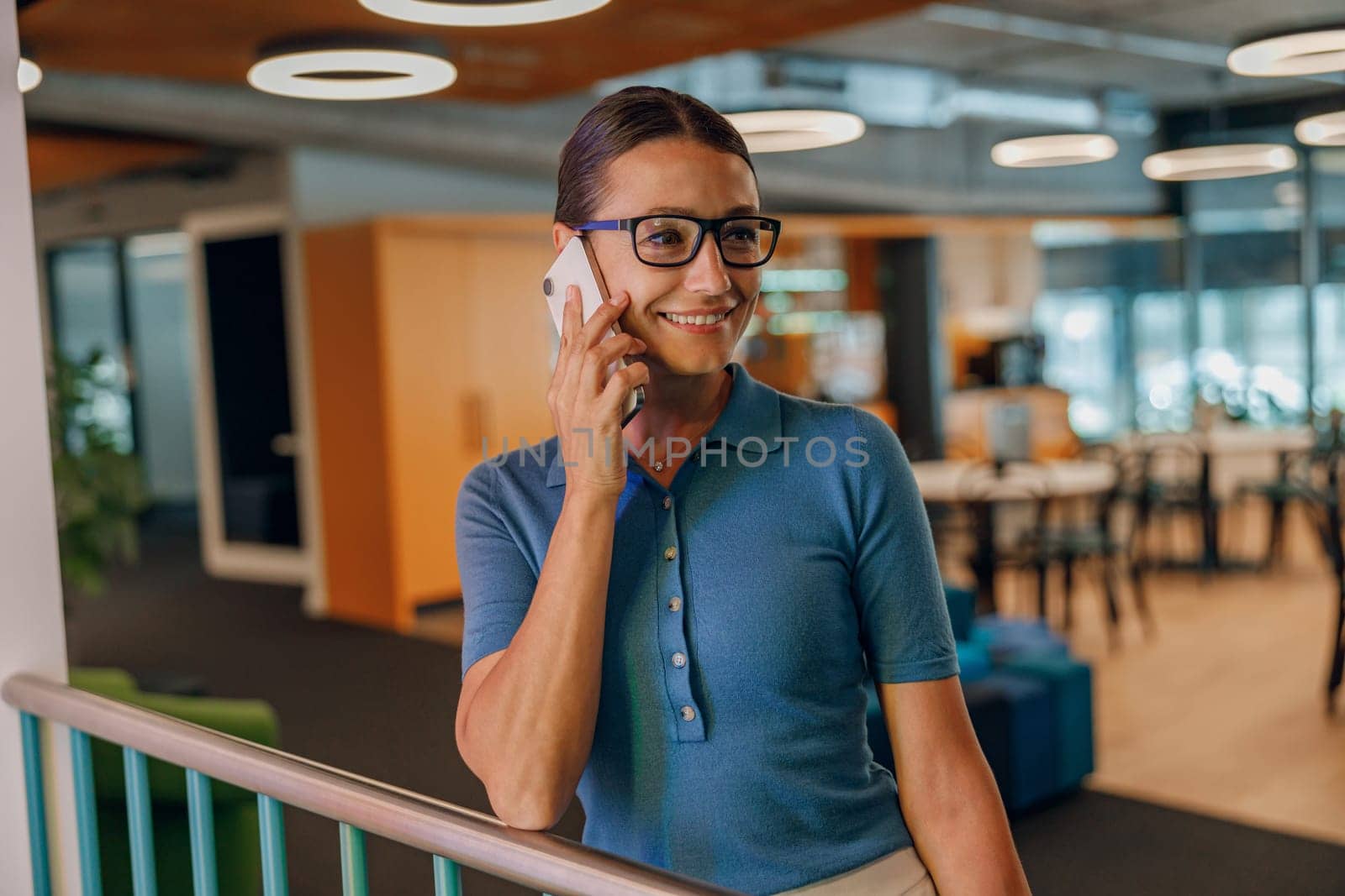 A person is actively engaging in a phone call within a modern, contemporary office setting that fosters collaboration