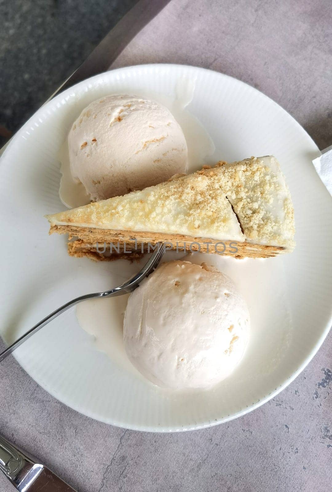 View from above of a tasty piece of cake and ice cream, on a plate with a fork