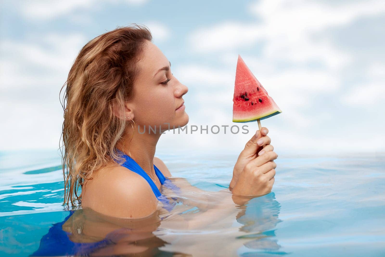 a girl in a bathing suit swims in the pool in a hot summer, a girl with a watermelon, summer holiday concept