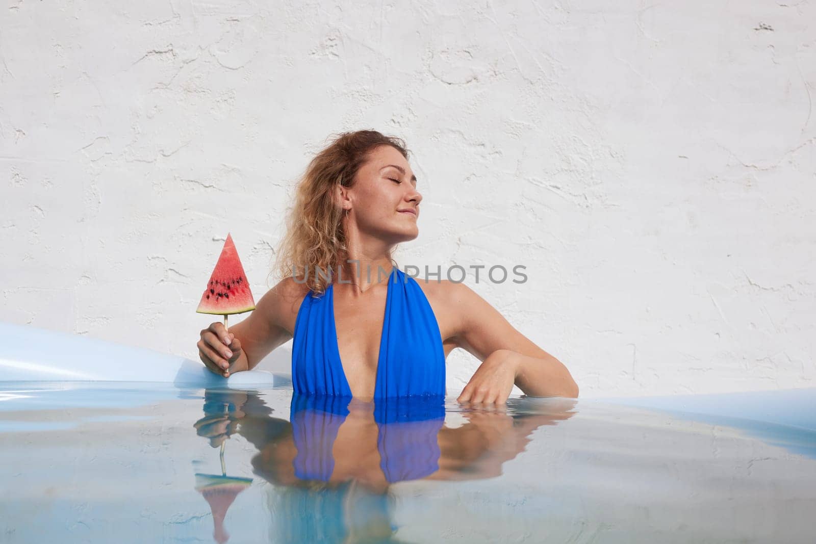 a girl in a bathing suit swims in the pool in a hot summer, a girl with a watermelon, summer holiday concept