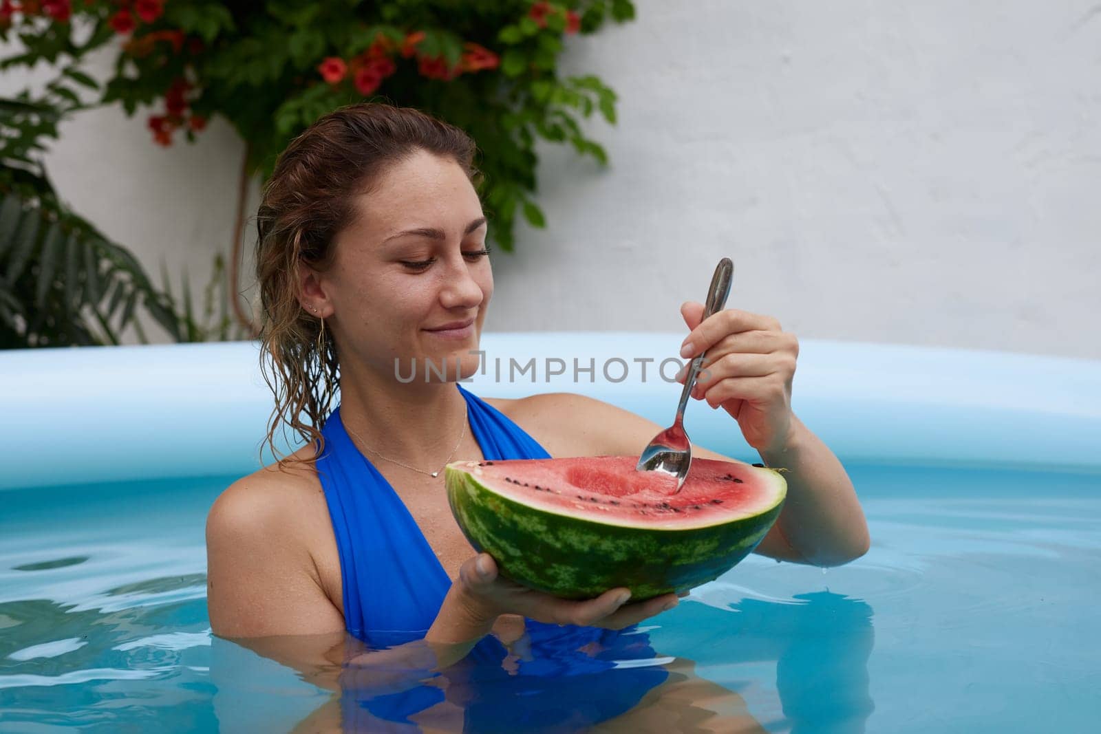 a girl in a bathing suit swims in the pool in a hot summer, a girl with a watermelon, summer holiday concept