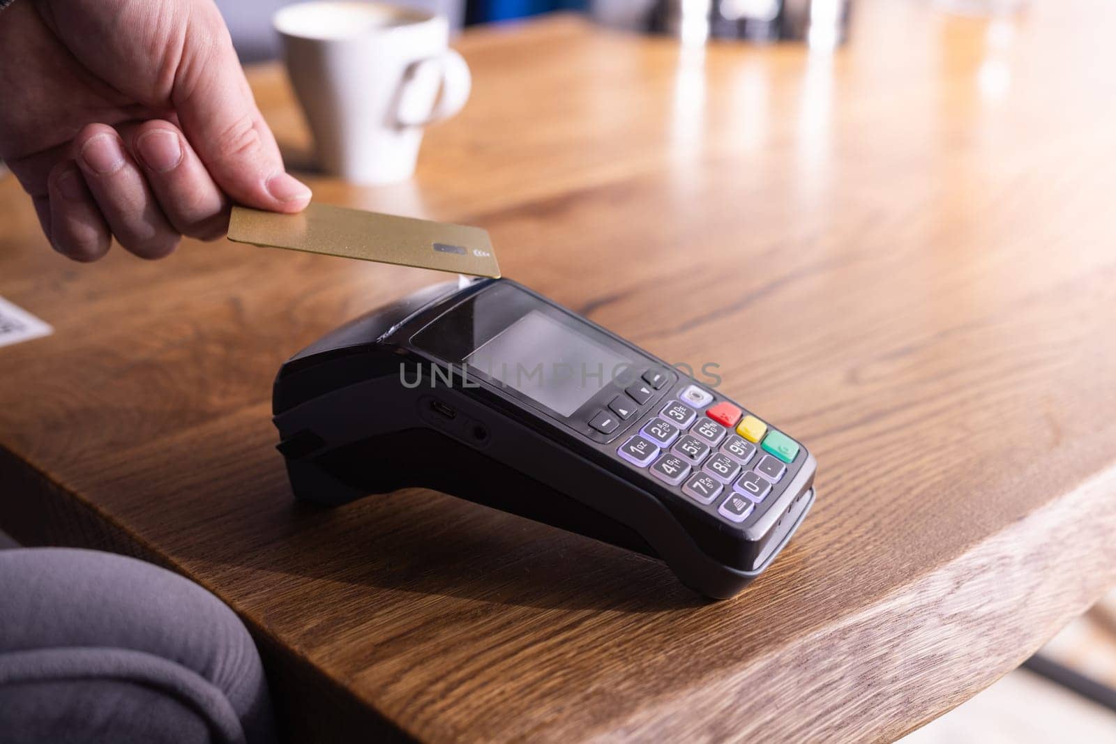 NFC credit card payment. Woman paying with contactless credit card with NFC technology. Wireless money transaction. Card machine in male hand on sunlight background
