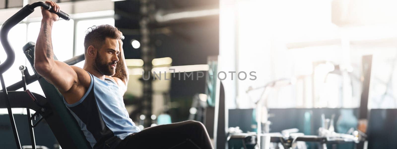 Healthy lifestyle and sport concept. Young man exercising with training apparatus in gym, empty space