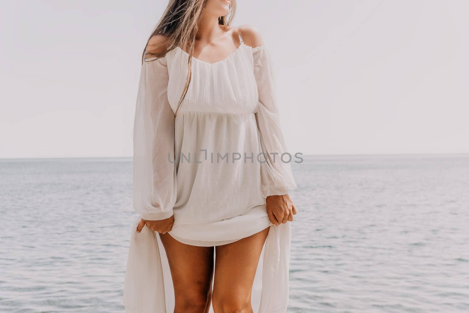 Woman travel sea. Young Happy woman in a long red dress posing on a beach near the sea on background of volcanic rocks, like in Iceland, sharing travel adventure journey