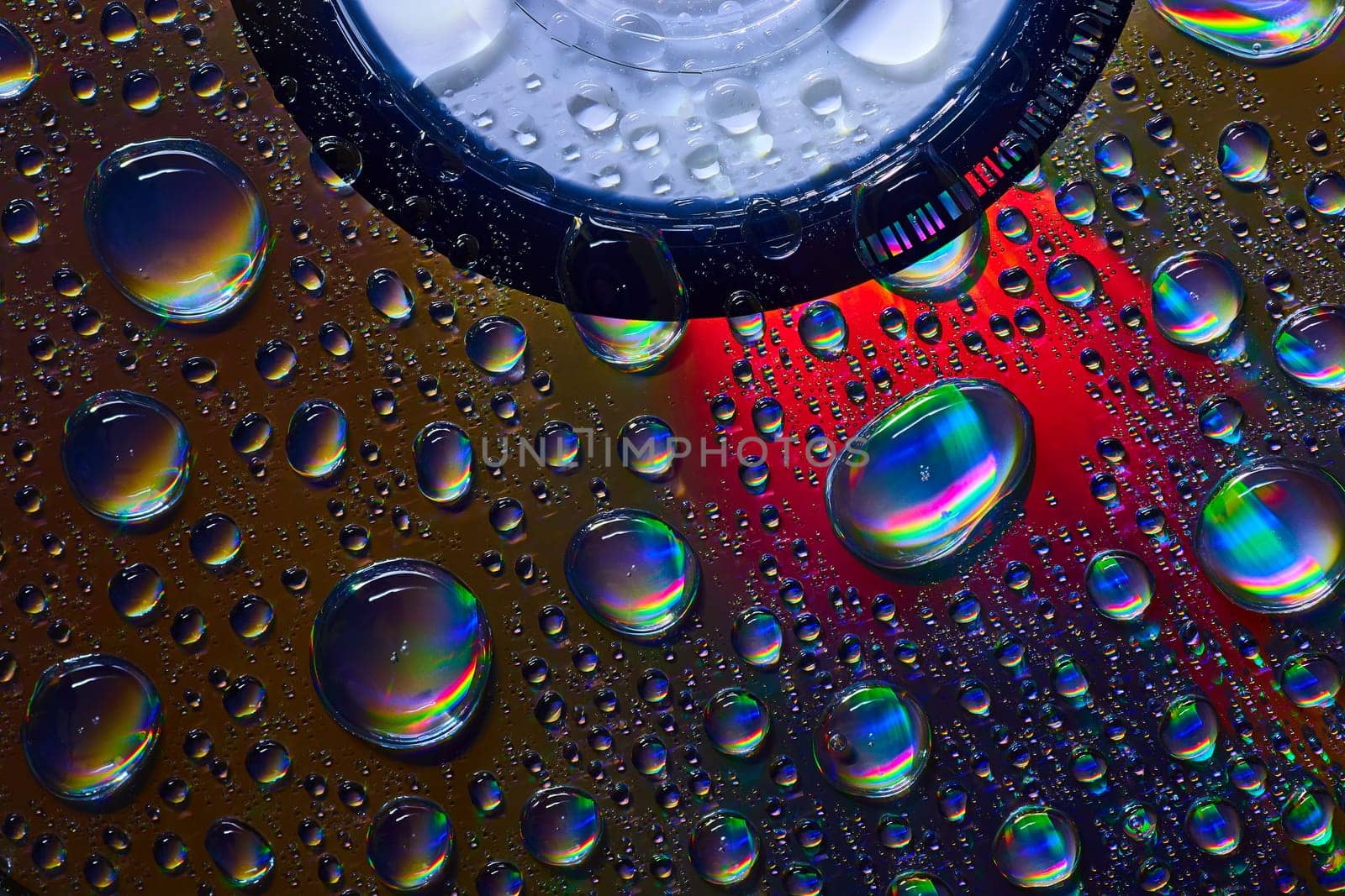Image of Dark silvery water drops on abstract CD surface with rainbow colors background asset