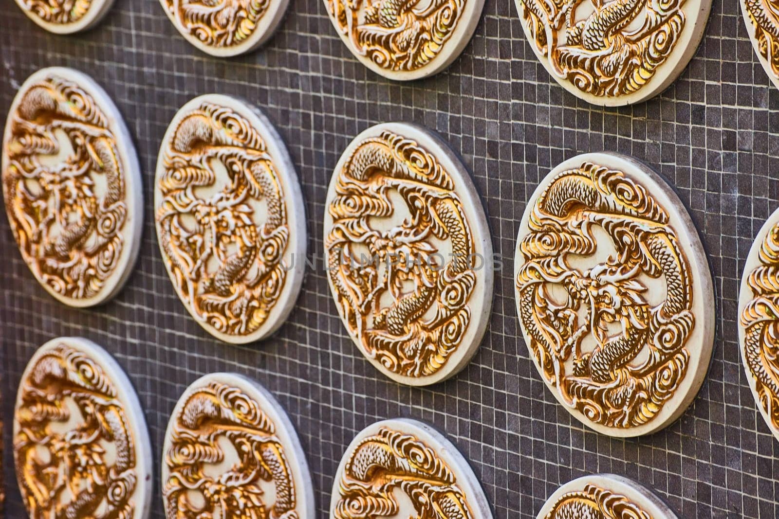 Image of Side view of several gold Chinese dragon coins on black tile wall