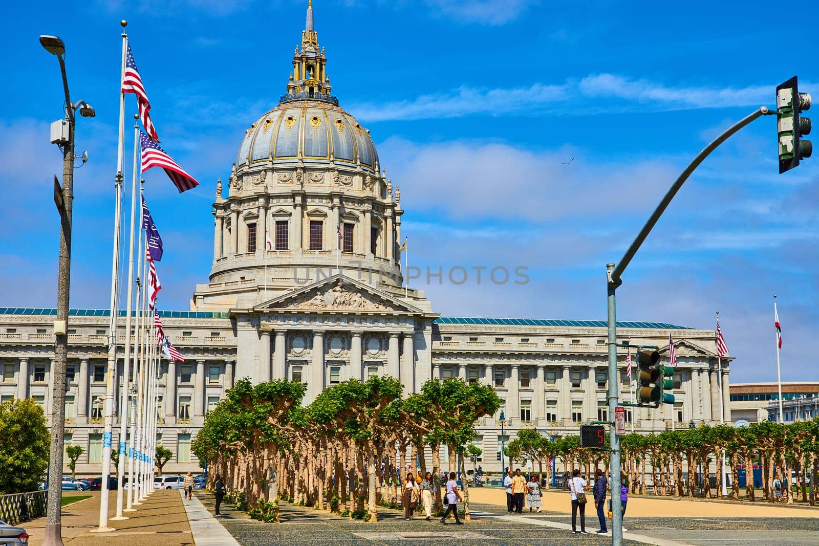Image of City hall entrance with trees and pedestrian and variety of flags on blue sky day with purple clouds