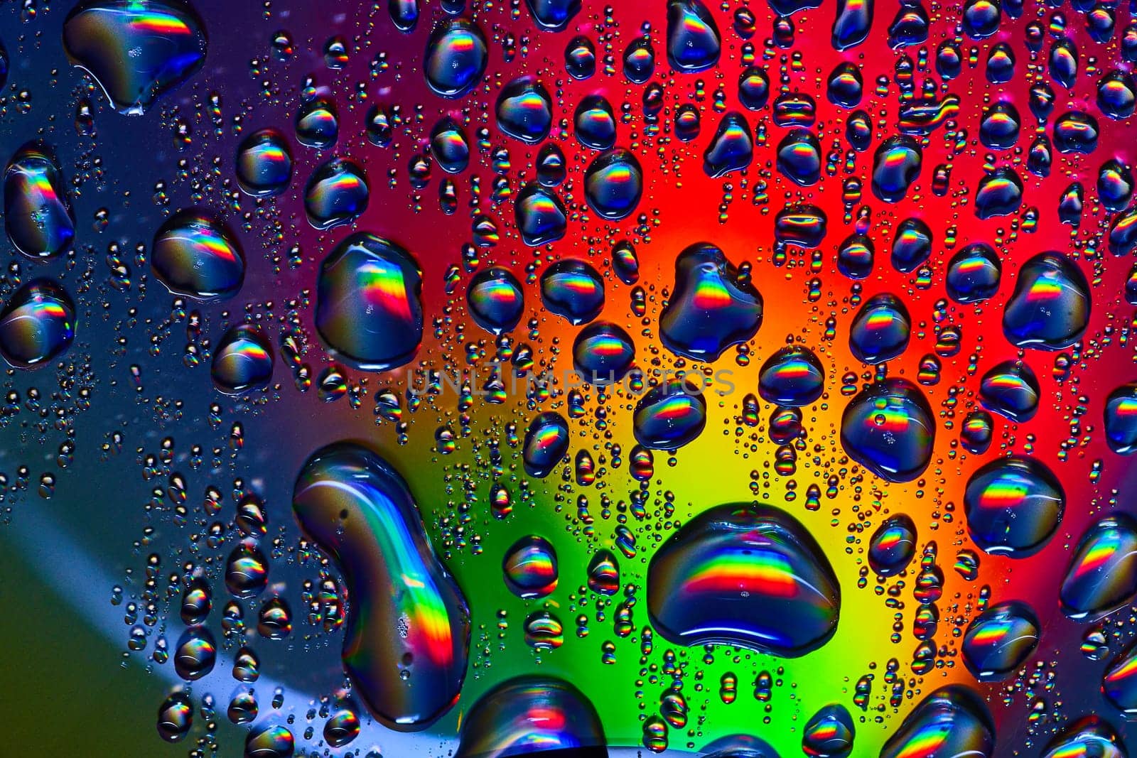 Image of Fizzy odd shaped bubbles bursting across rainbow colored metallic surface background asset