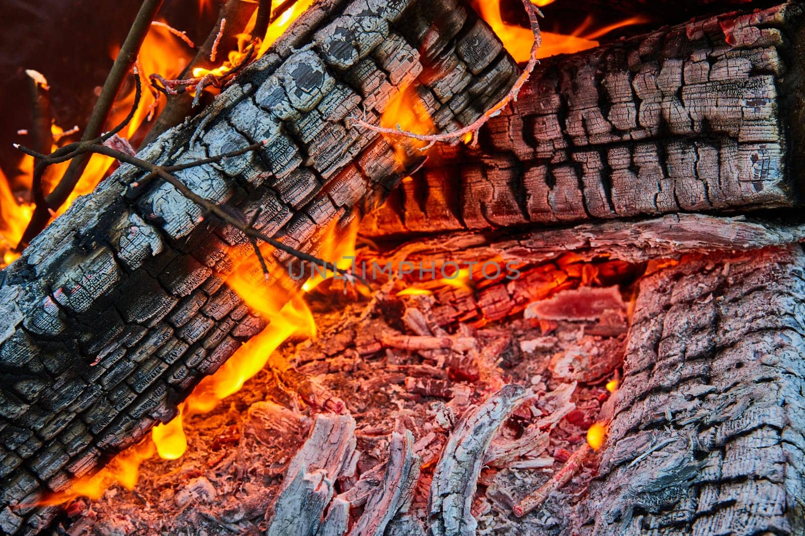 Image of Close up of ash covered logs with yellow and orange flames and red embers background asset