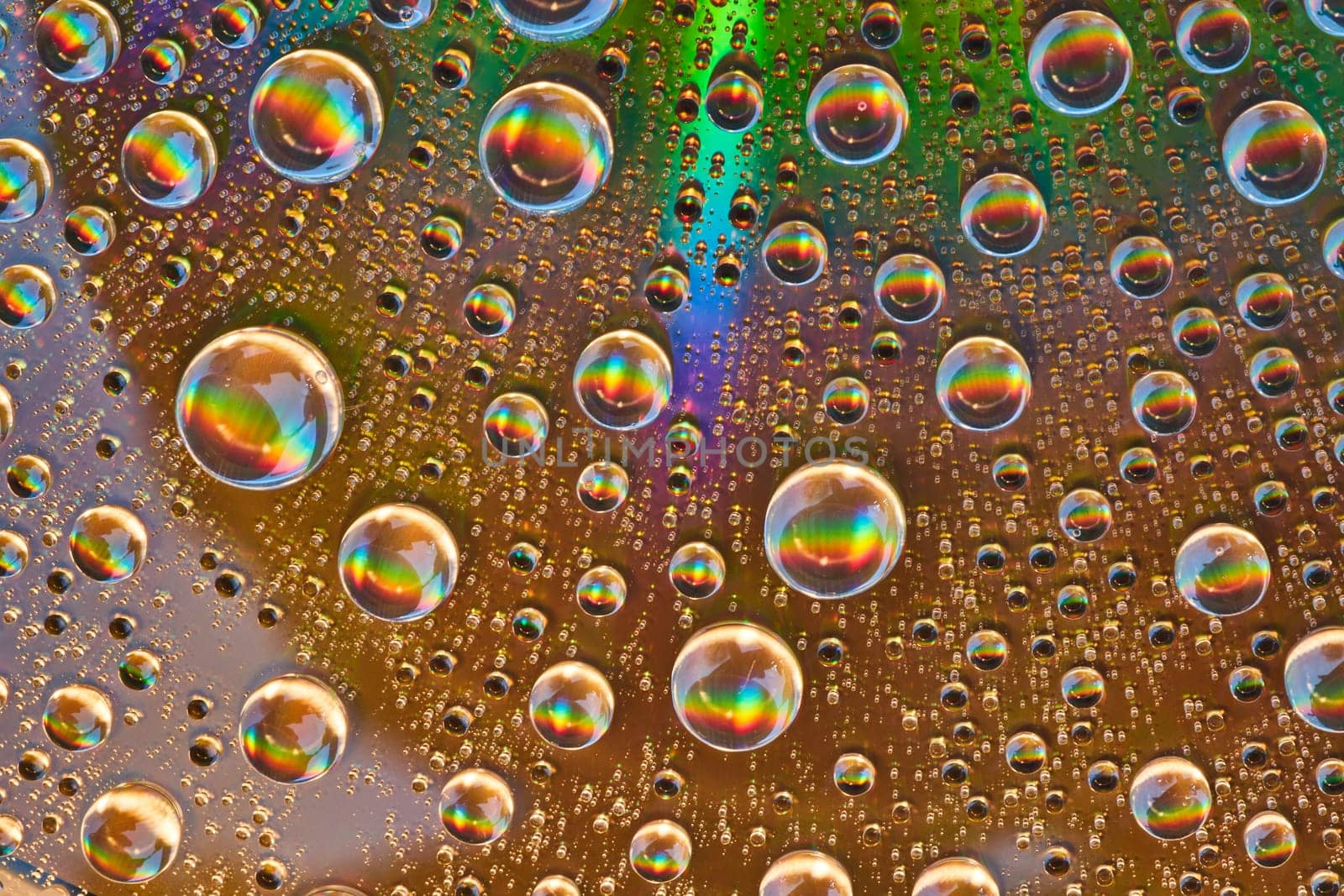 Image of Rainbow bursts inside water drops on reflective metal surface