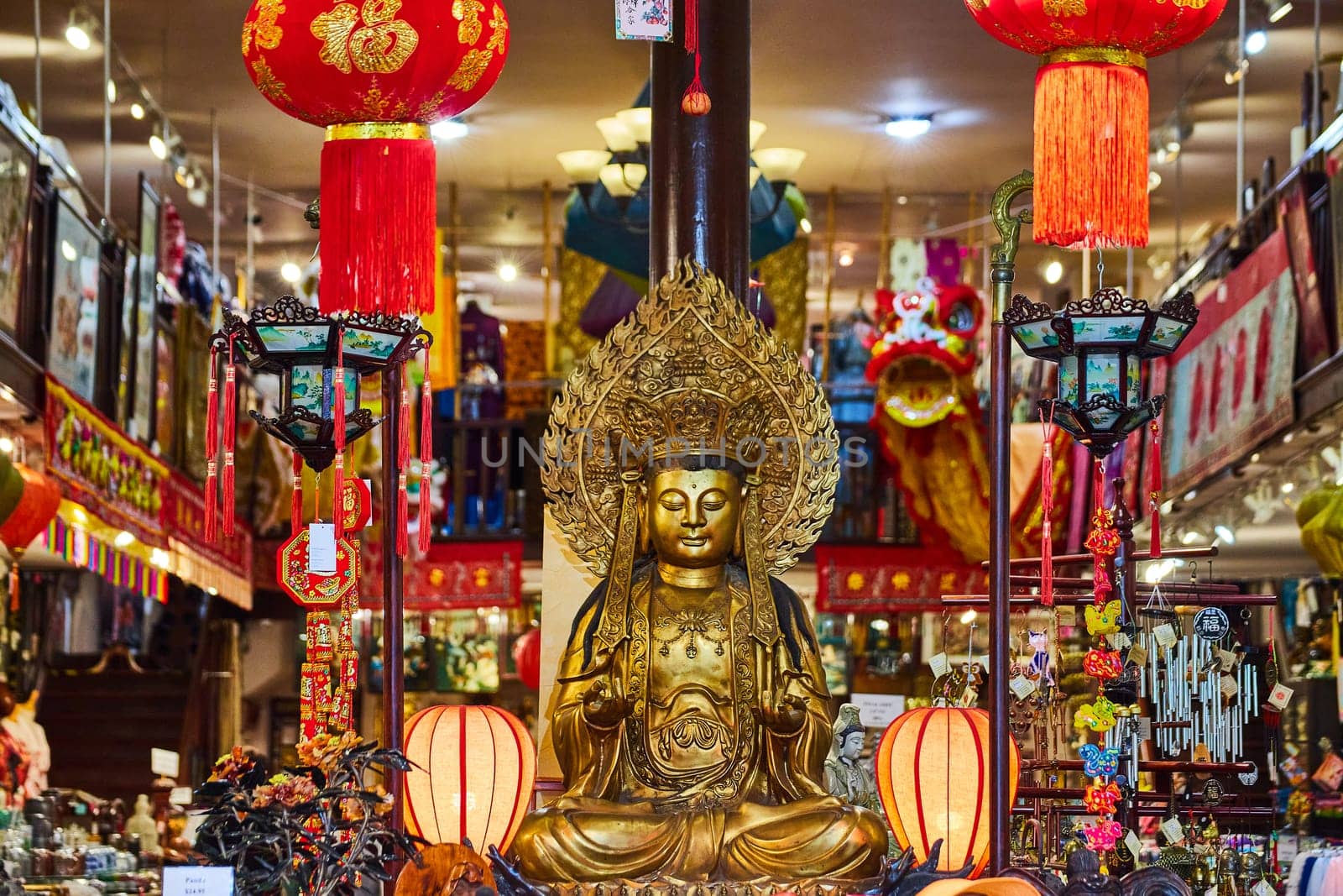 Image of Vibrant interior of Chinatown shop with giant golden buddha surrounded by wind chimes