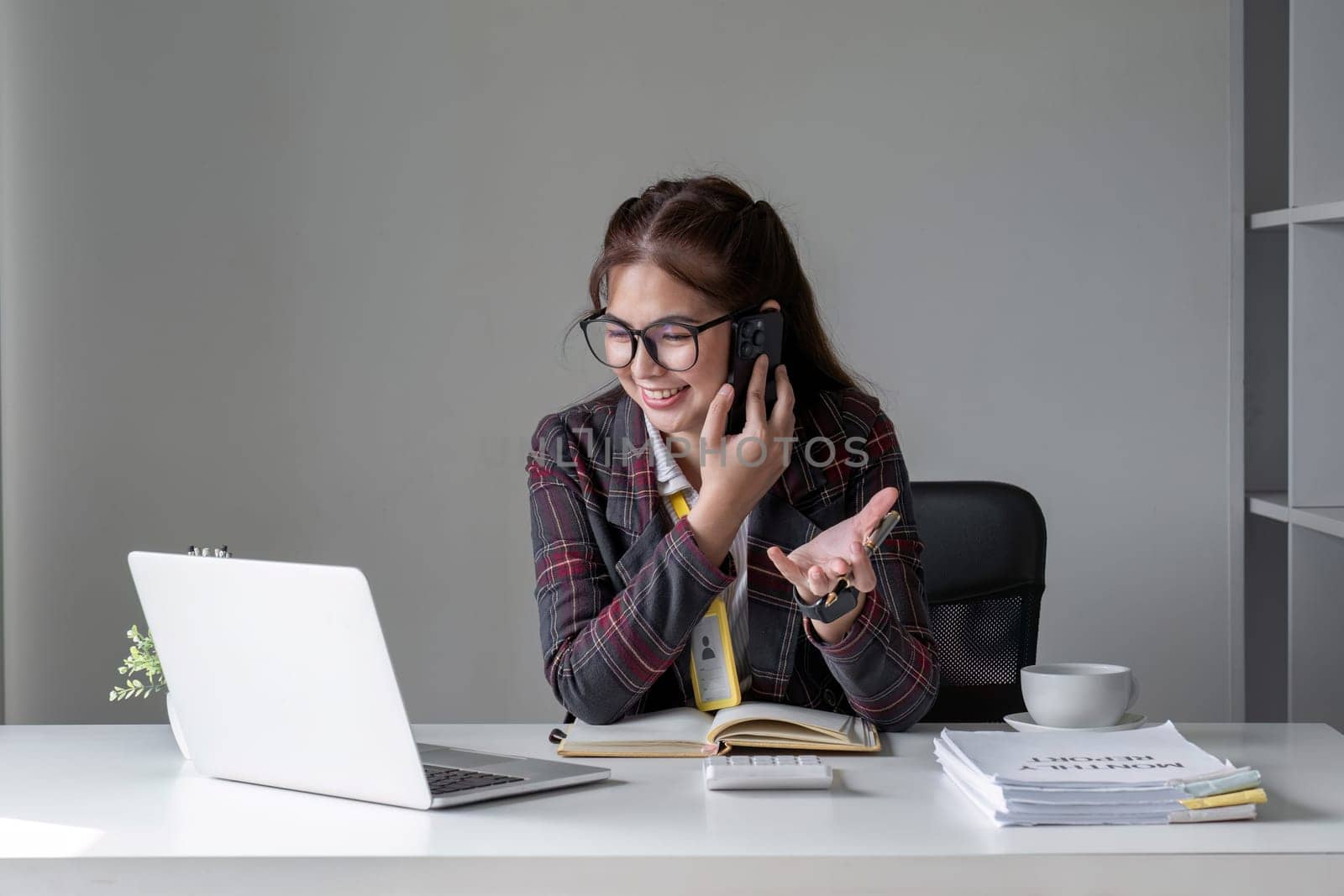 Young businesswoman smiling and talking on mobile phone in office.