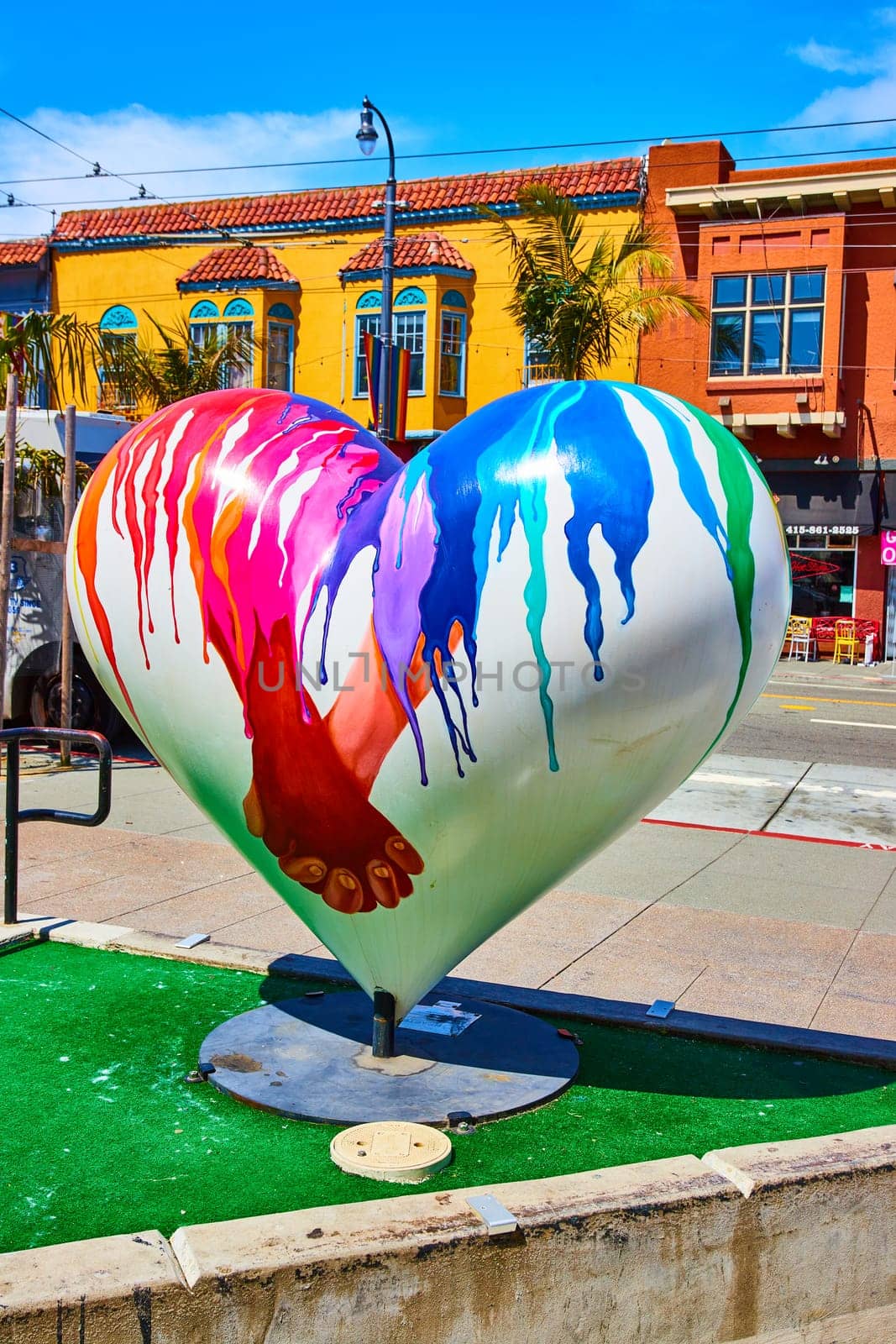 Image of Castro District heart sculpture with bright blue sky and buildings behind it