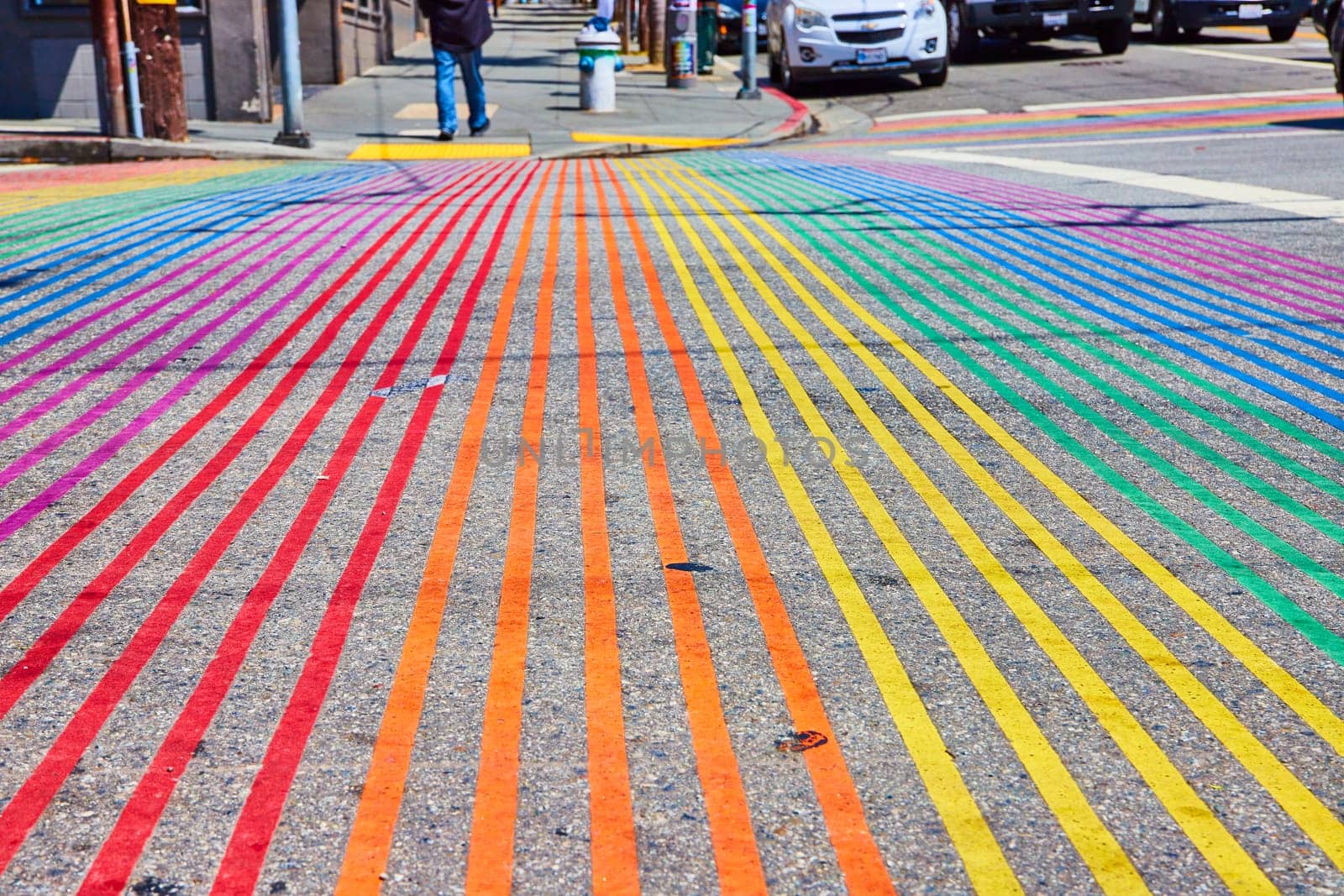 Image of Close up of streaks of color on concrete road with rainbow crosswalk and low view of cars