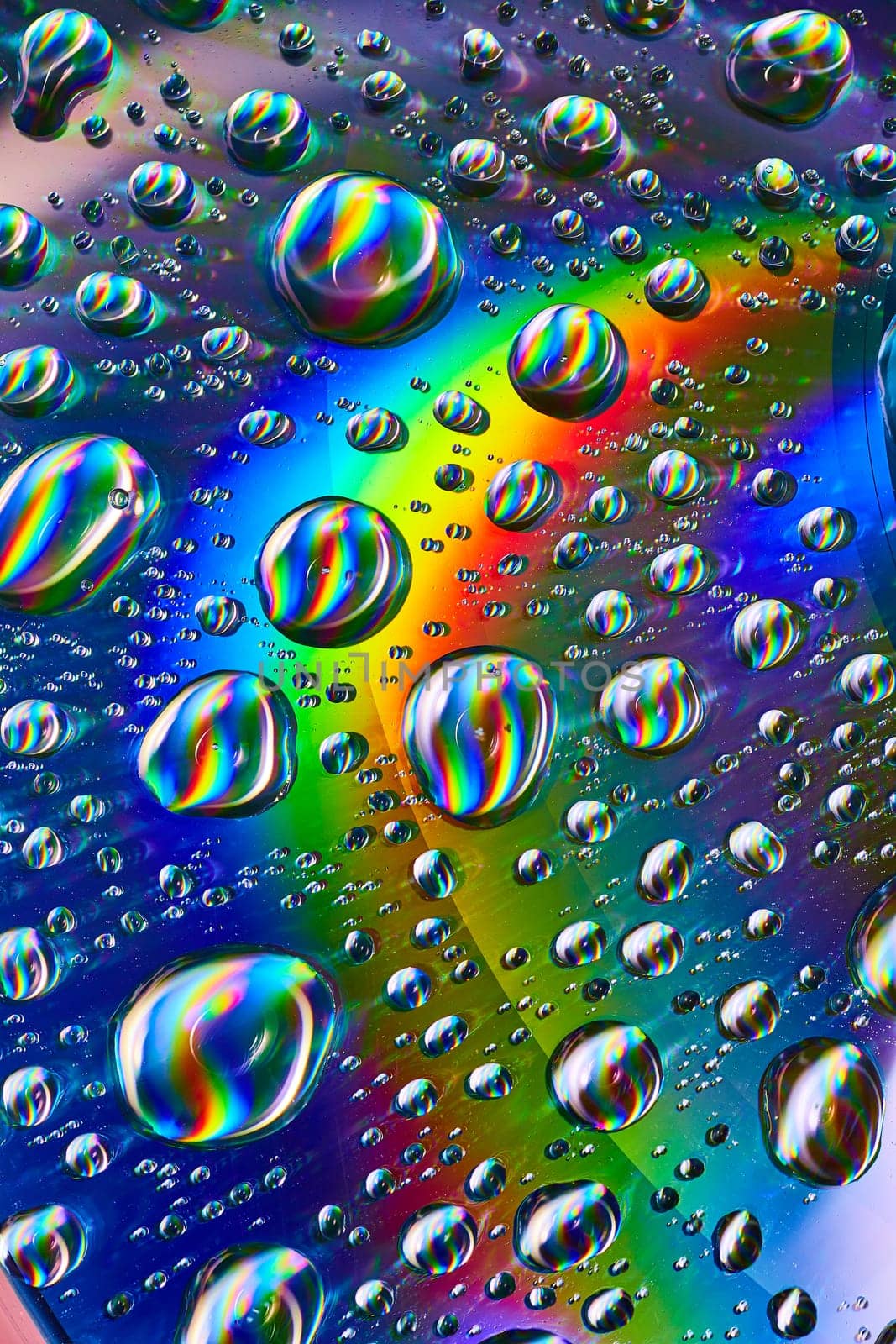 Image of Dark silvery swirling water drops in cosmic rainbow Saturn ring in psychedelic background asset