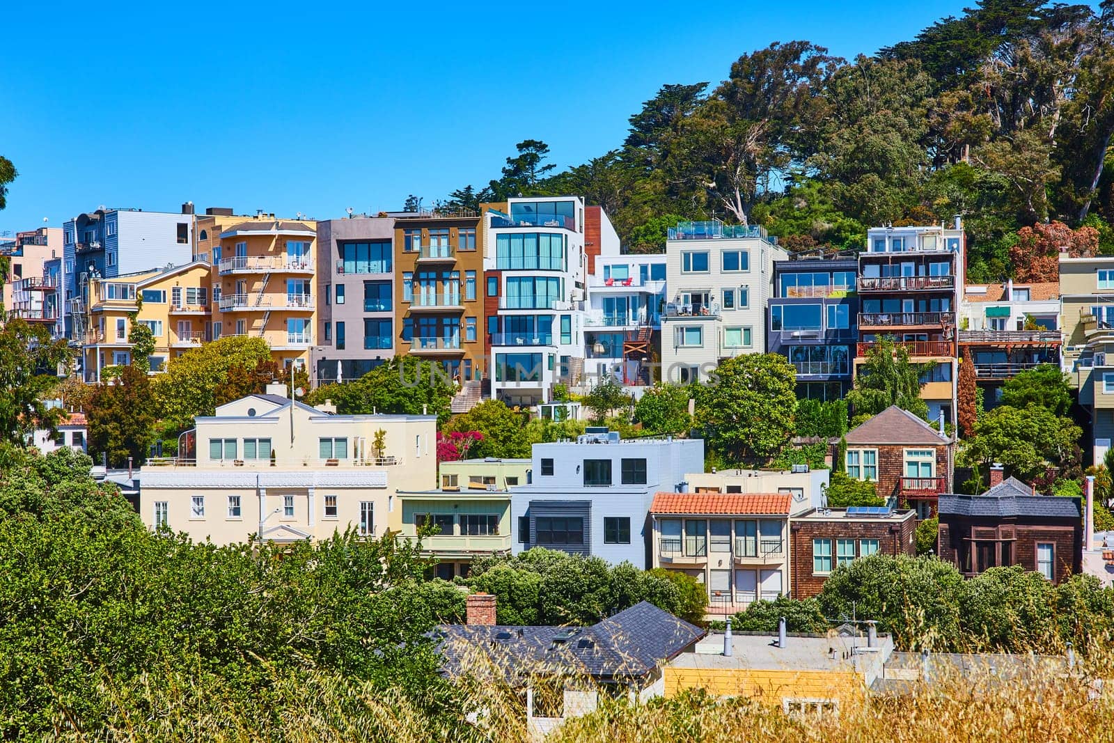 Image of Colorful neighborhood apartments on different tiers of hillside in Corona Heights under blue sky