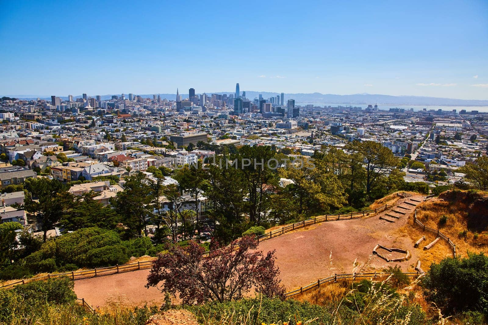 Image of Park trail with fire pit and logs with view of San Francisco city and downtown skyscrapers
