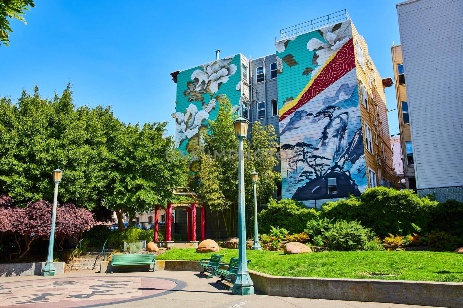 Image of Peaceful and zen art mural on buildings overlooking sunny park with red Chinese pergola