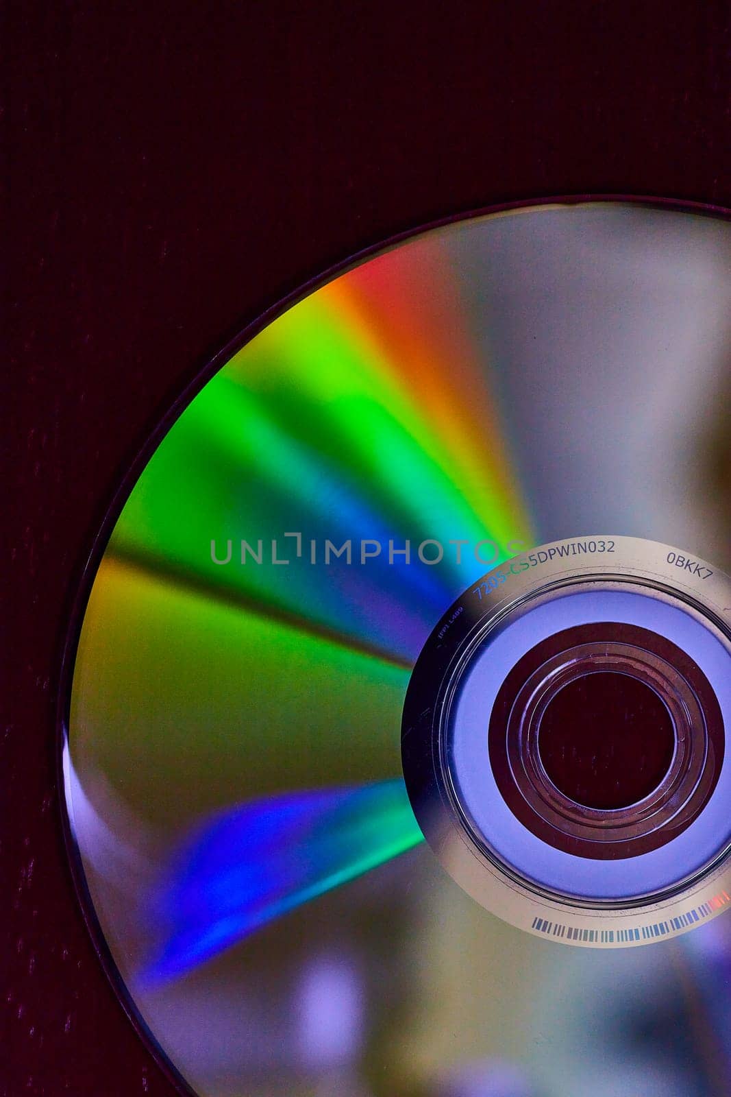 Image of Silver CD on dark background with burst of rainbow colored light across surface