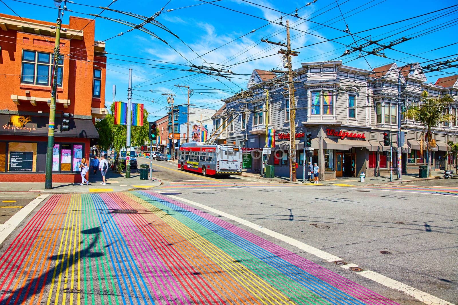 Image of Rainbow crosswalk and view across street with bay windows with rainbow curtains