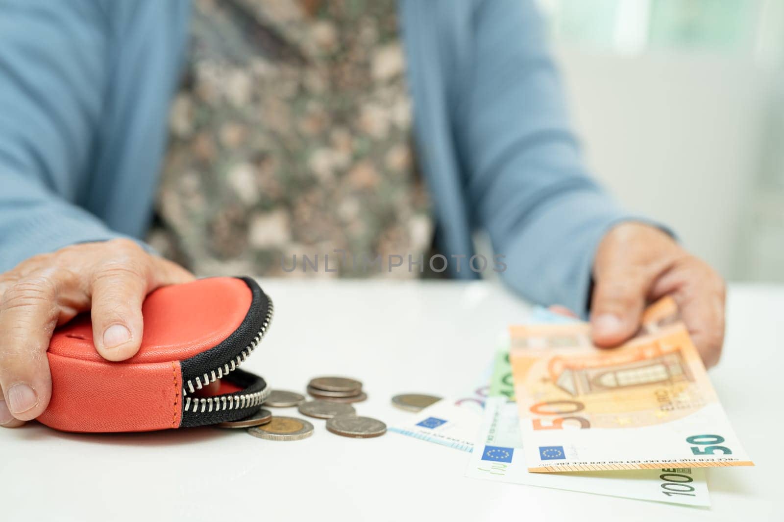 Asian senior woman holding counting coin money and Euro bnaknotes in purse. Poverty, saving problem in retirement. by pamai
