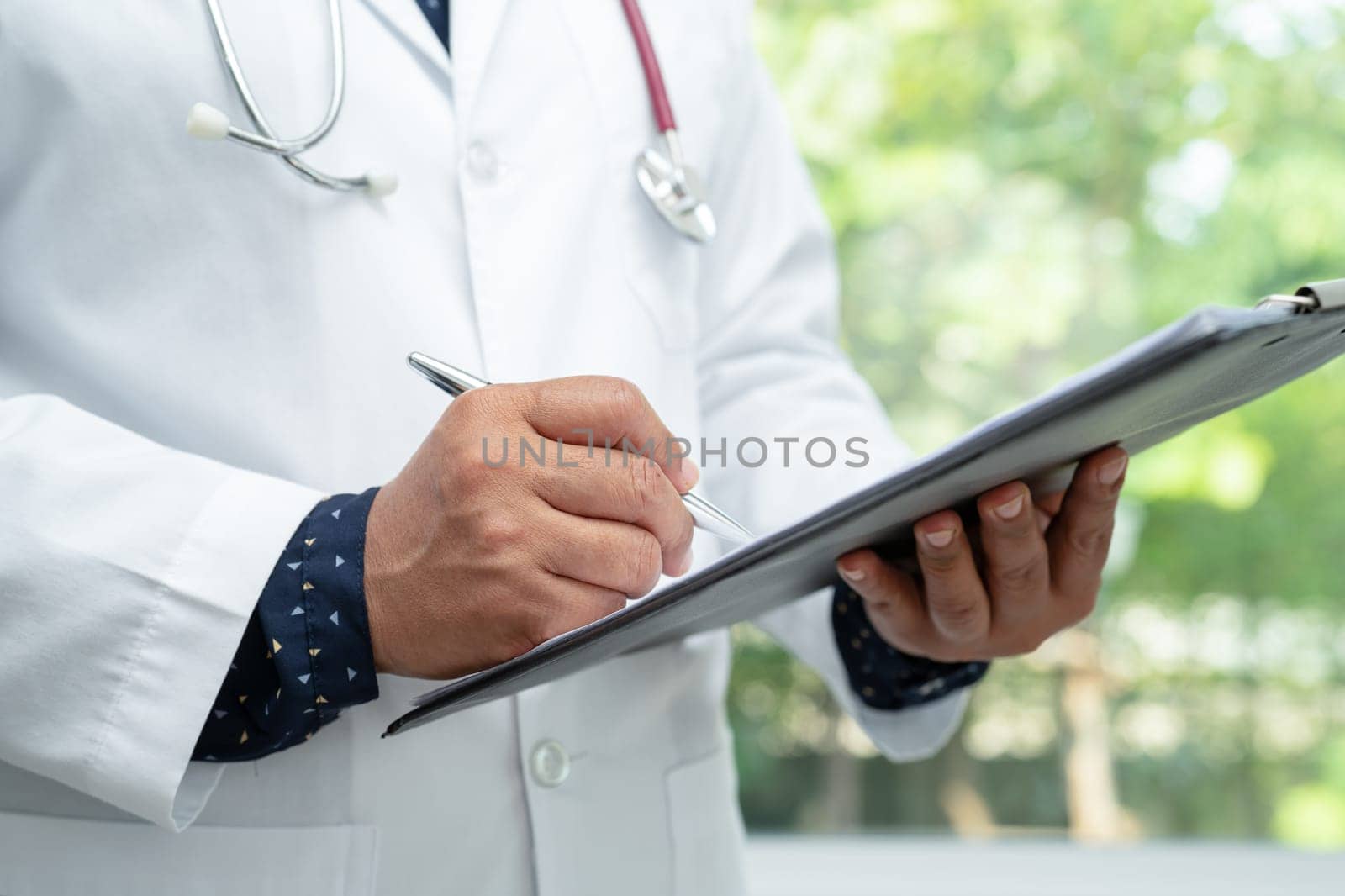Doctor checking and note diagnosis medicine in clipboard of patient in hospital. by pamai