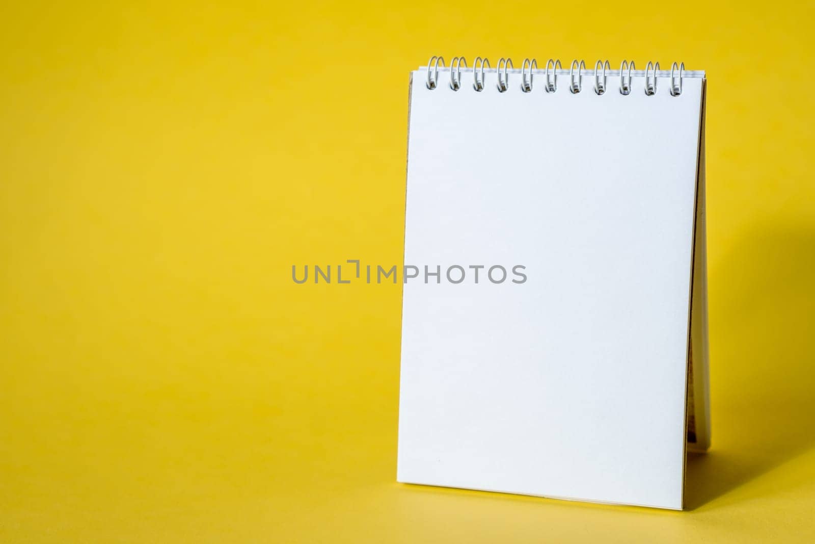 Opened notepad on a yellow background. Composition of writing to-dos for the day. The notebook lies on a plain background with space for writing.