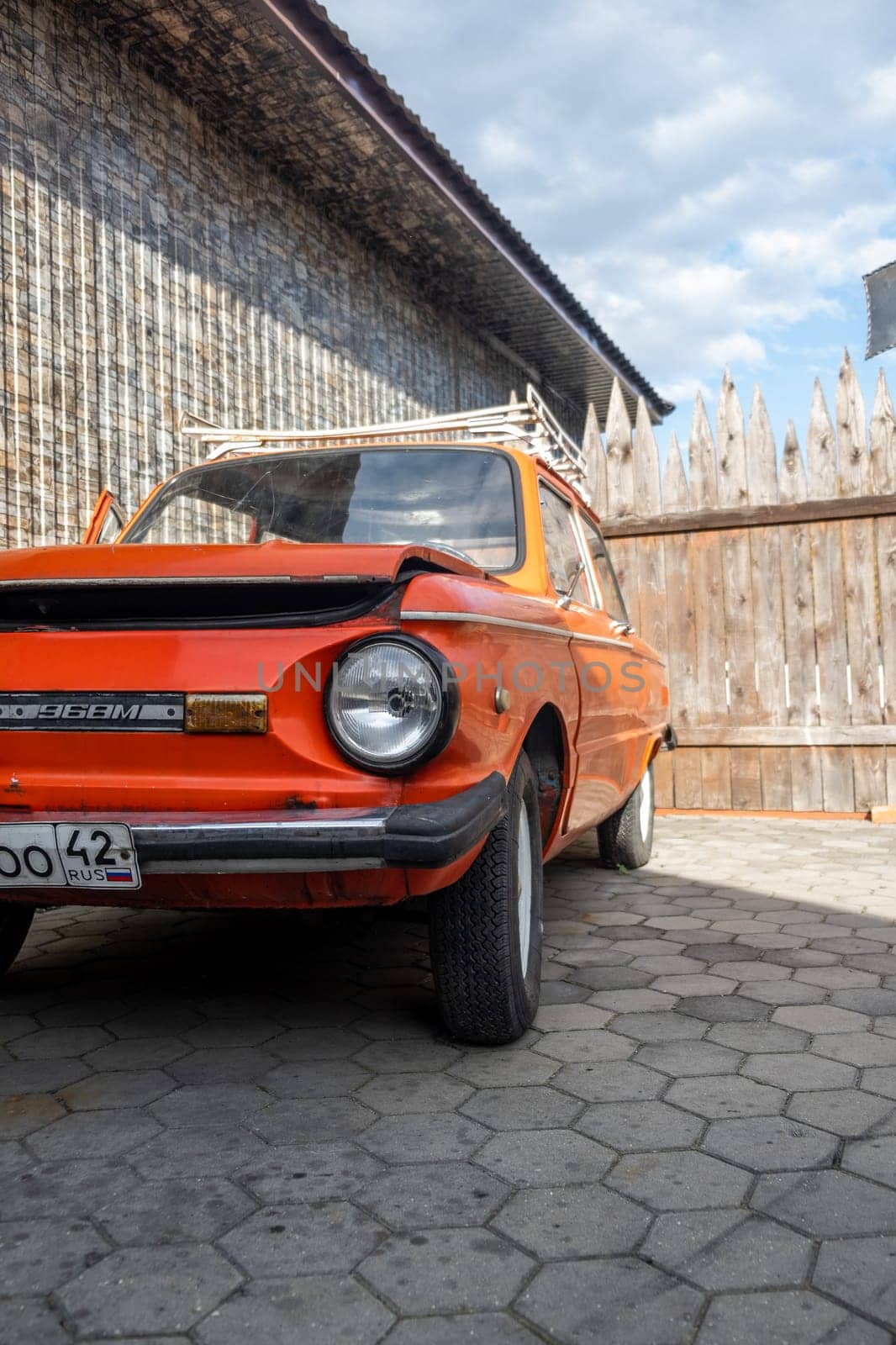 19.09.2023, Kemerovo, Russia. Red old Zaporozhets car in the yard on a sunny day. The car has round headlights.