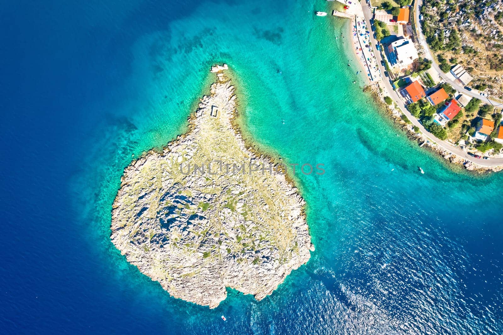 Small islet and Sveti Juraj turquoise beach under Velebit mountain aerial view, archipelago of Croatia