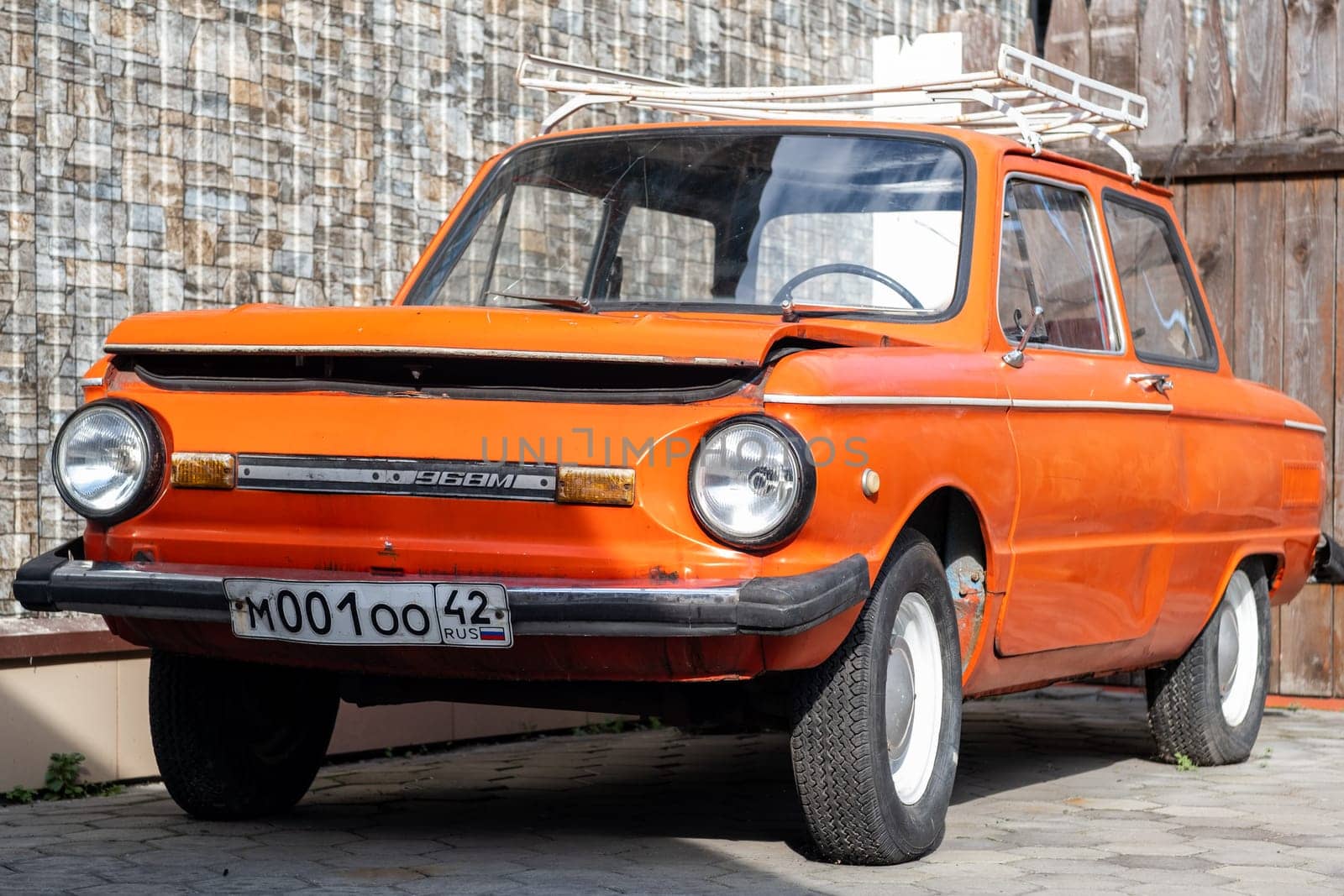 19.09.2023, Kemerovo, Russia. Red old Zaporozhets car in the yard on a sunny day. The car has round headlights.