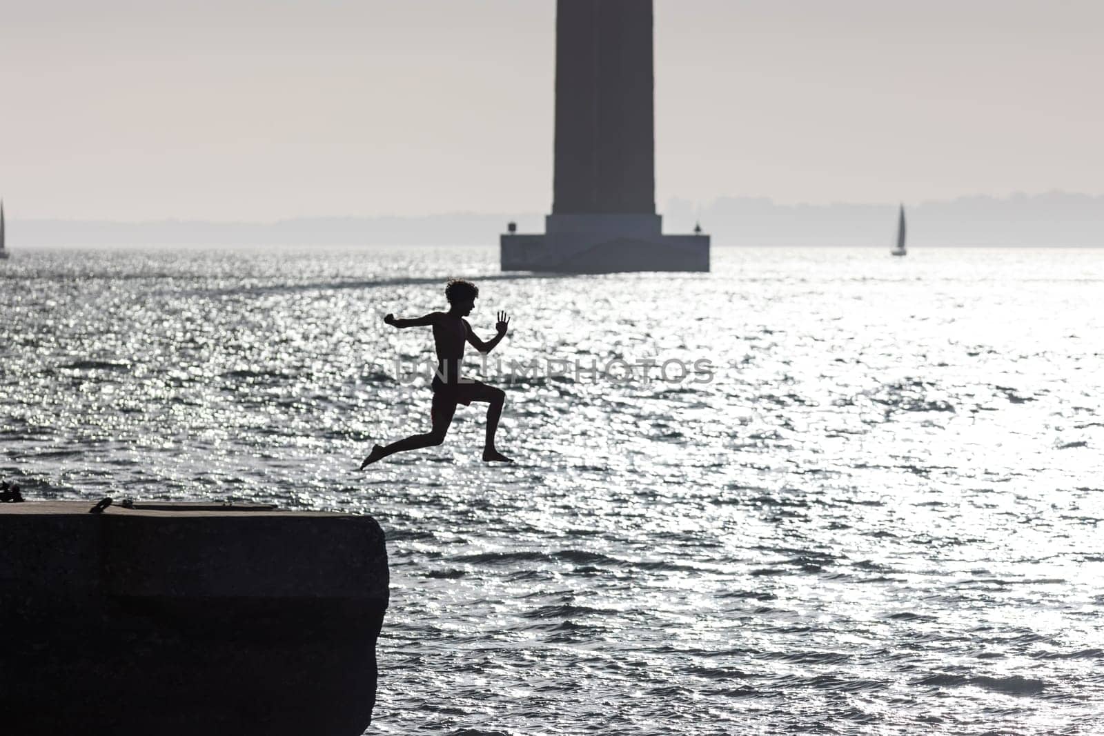 A boy jumps into the water with a takeoff run - monochrome image. Mid shot