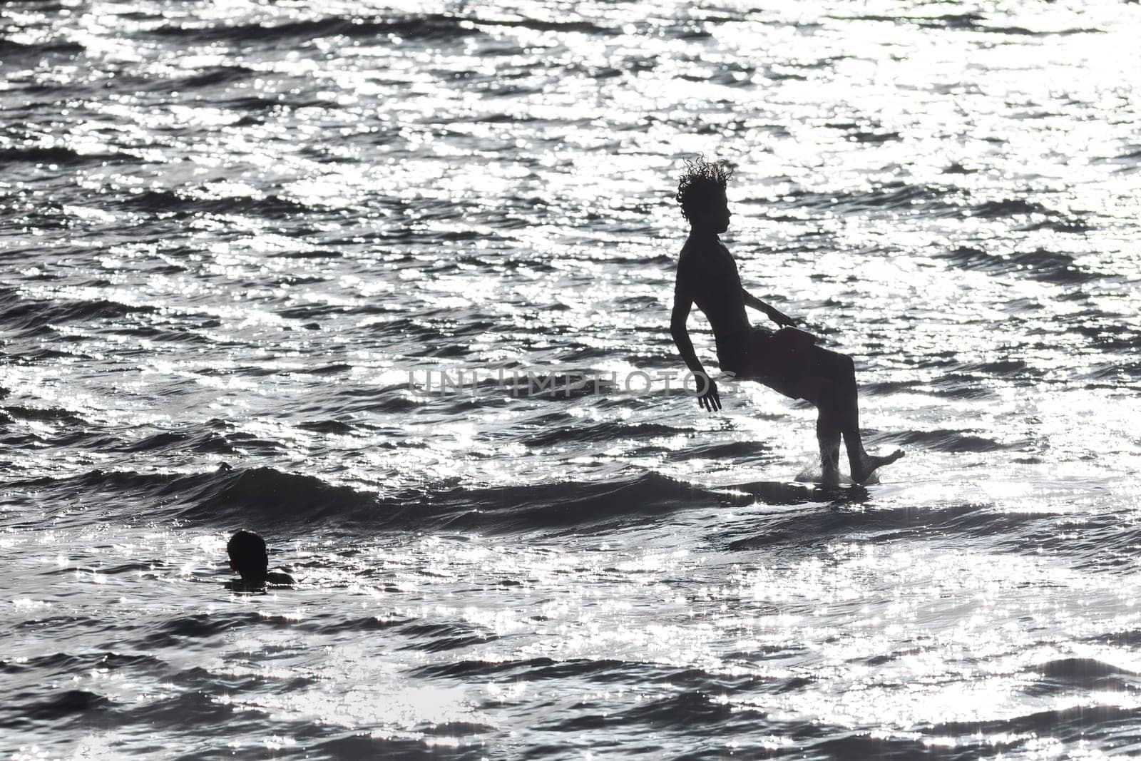 Boys jumping into the water - monochrome image. Mid shot