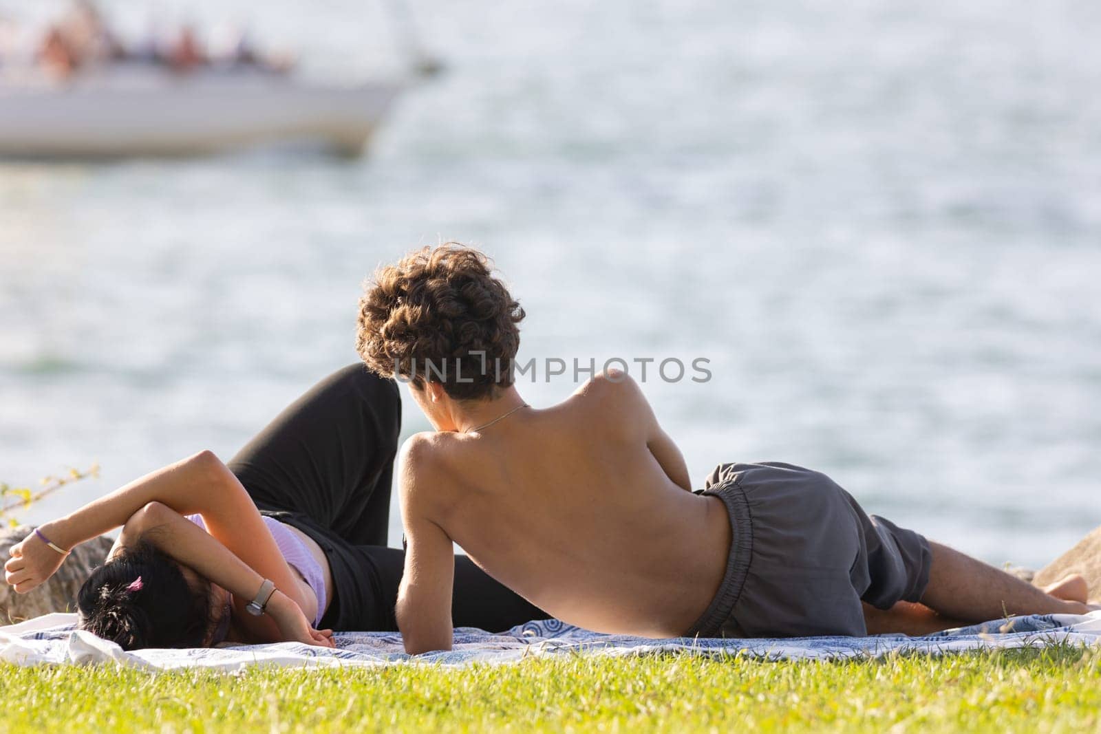 Young couple having a rest on the cliff by the sea. Mid shot