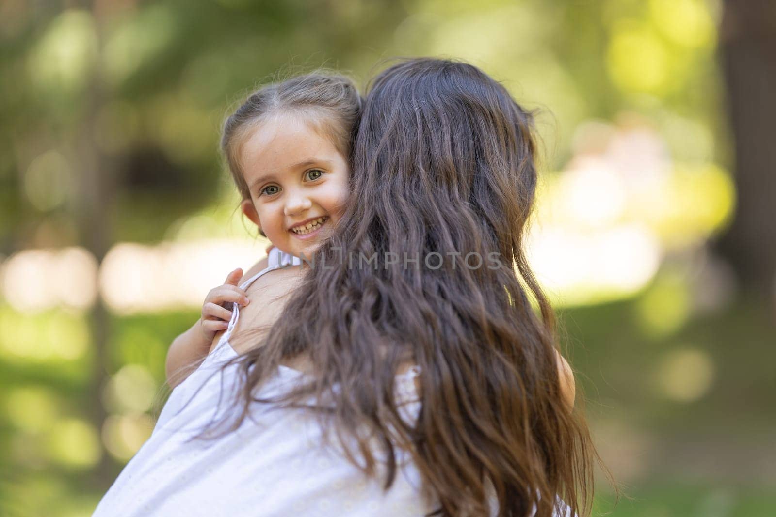 Mom hugging her daughter in the park. Mid shot