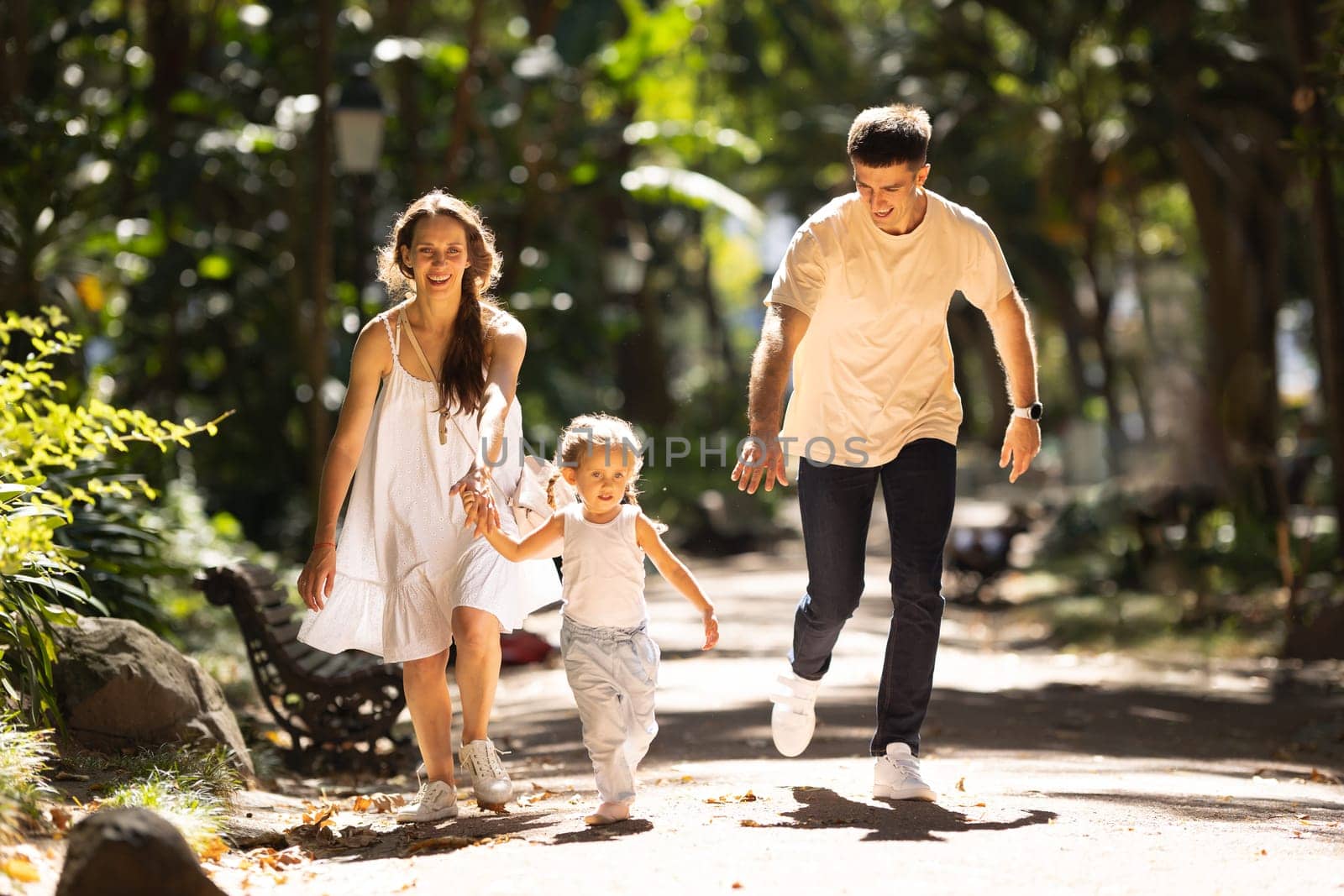 Young family running in the summer park. Mid shot