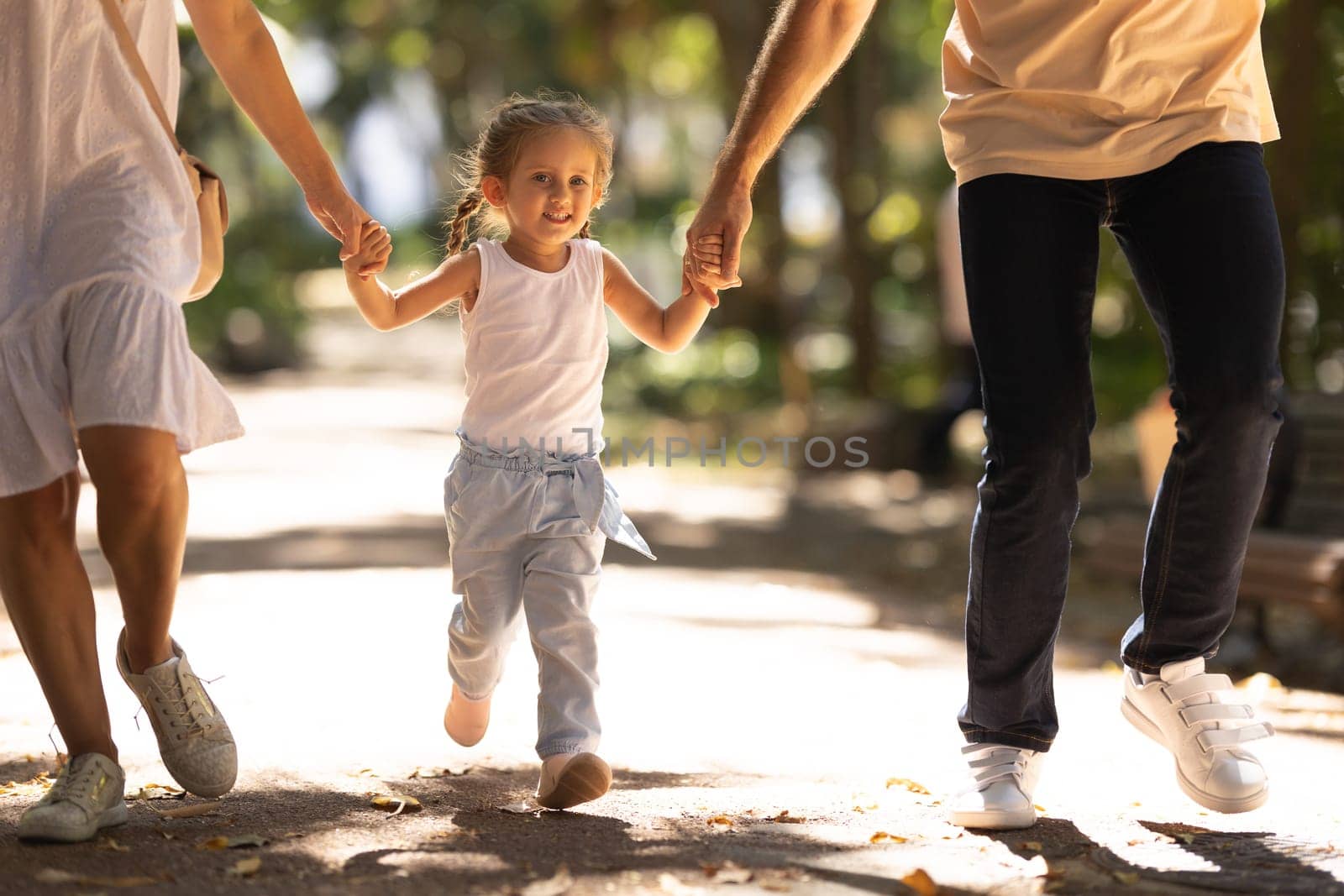 Young and happy family walking in a summer park holding hands by Studia72