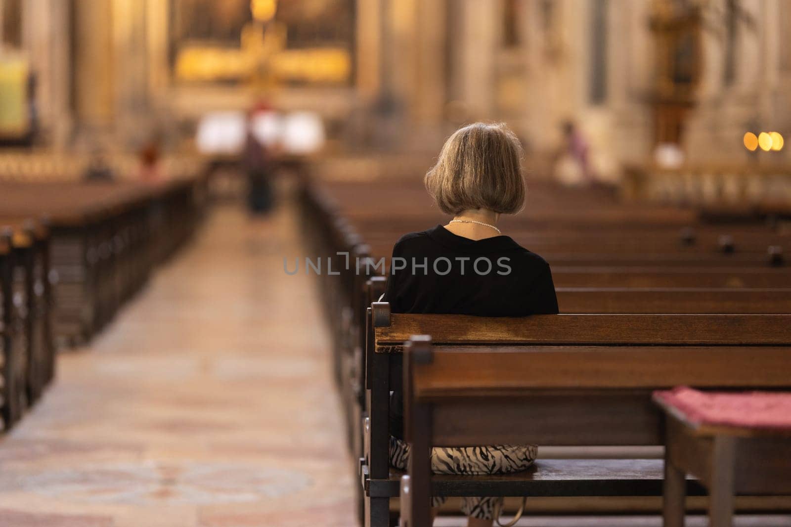 A woman sits in a church during a sermon. Mid shot