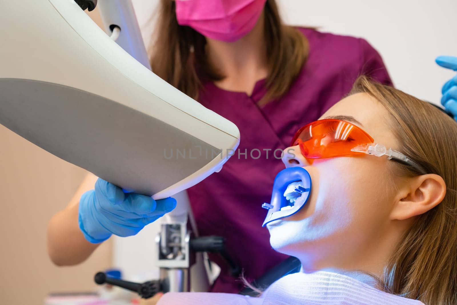 Teeth whitening for woman and application of laser bleaching teeth at dentist clinic