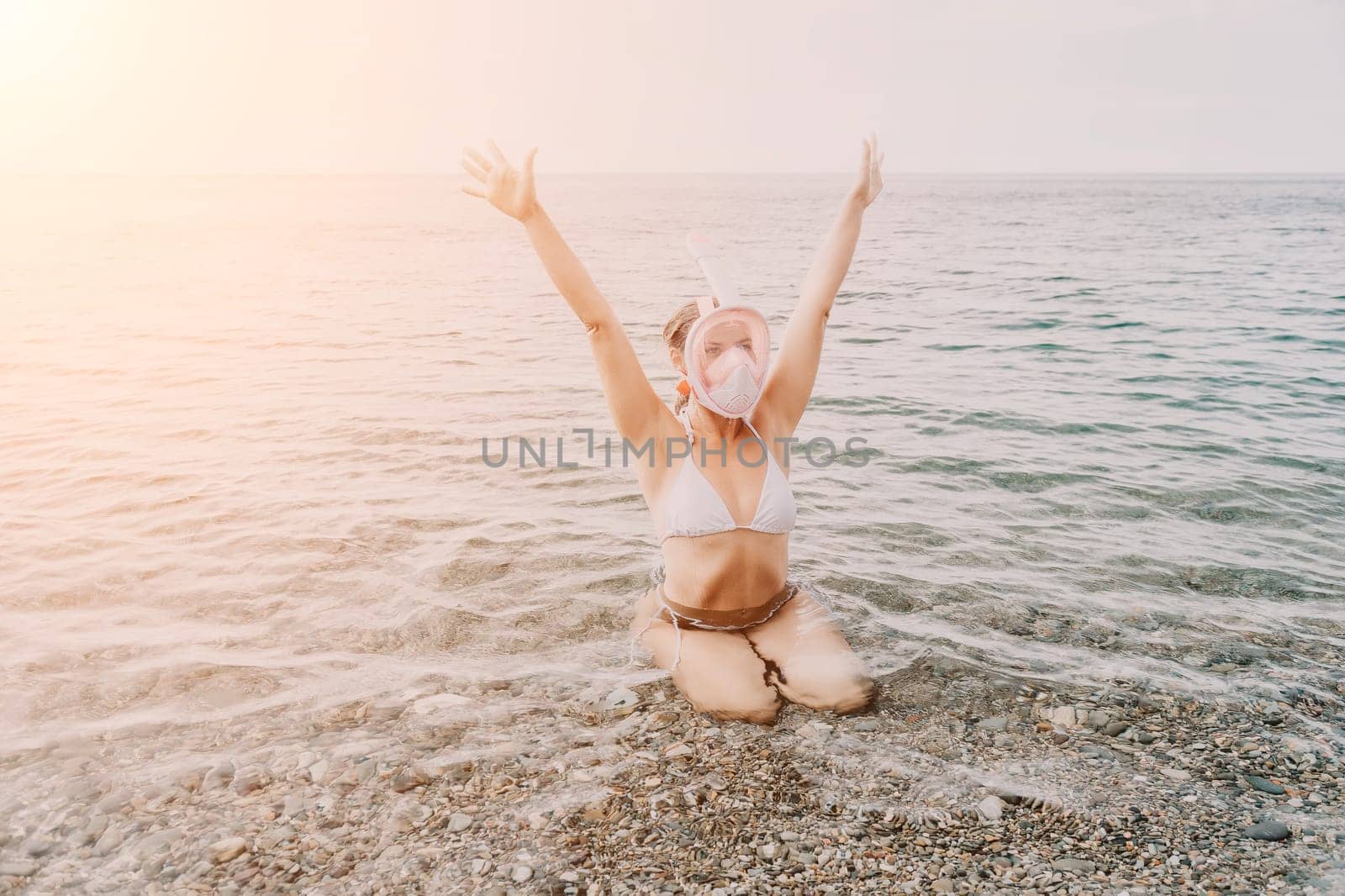 Young happy woman in white bikini put pink snorkeling mask on beach before swimming. girl having fun relaxing on beautiful beach. Beach lifestyle