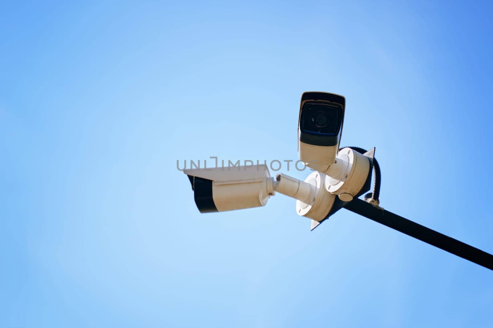 A stunning and striking view of modern surveillance cameras positioned perfectly under a clear blue sky