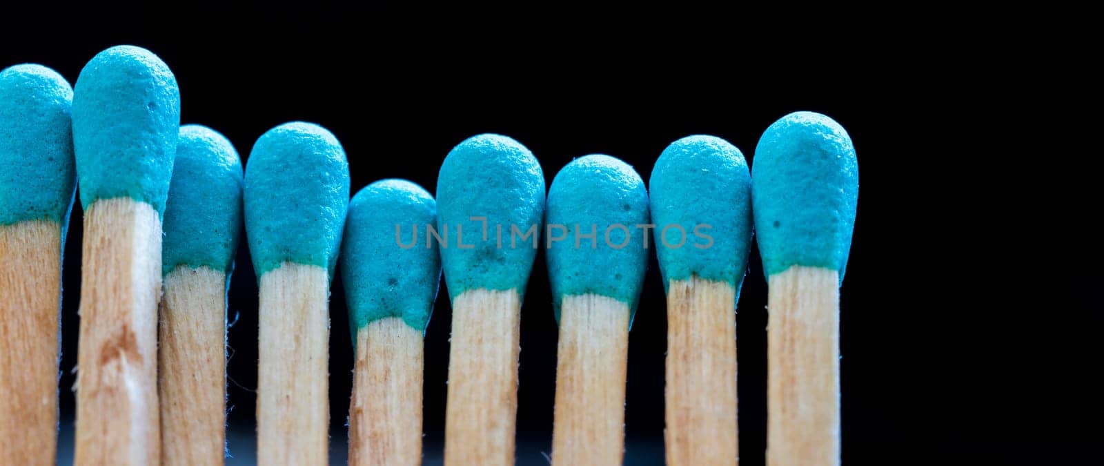 a row of blue matches on black background. Concept