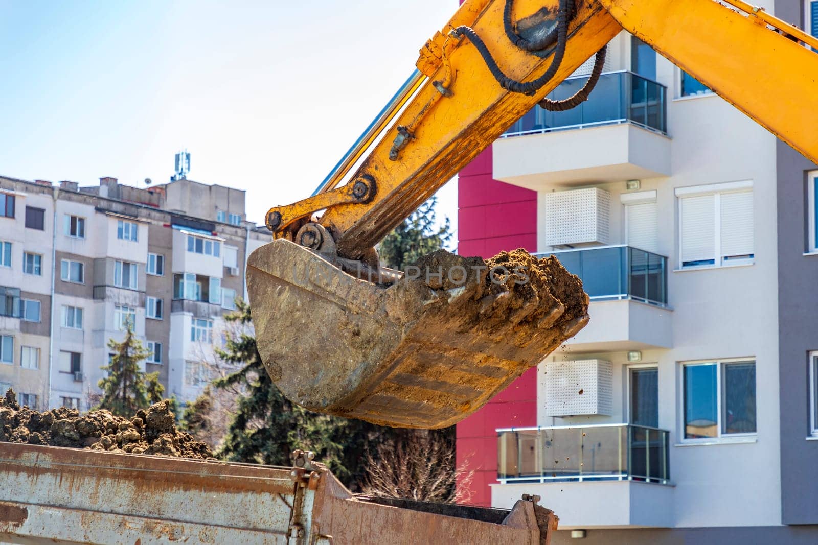 an excavator fills a dump truck with earth. Close