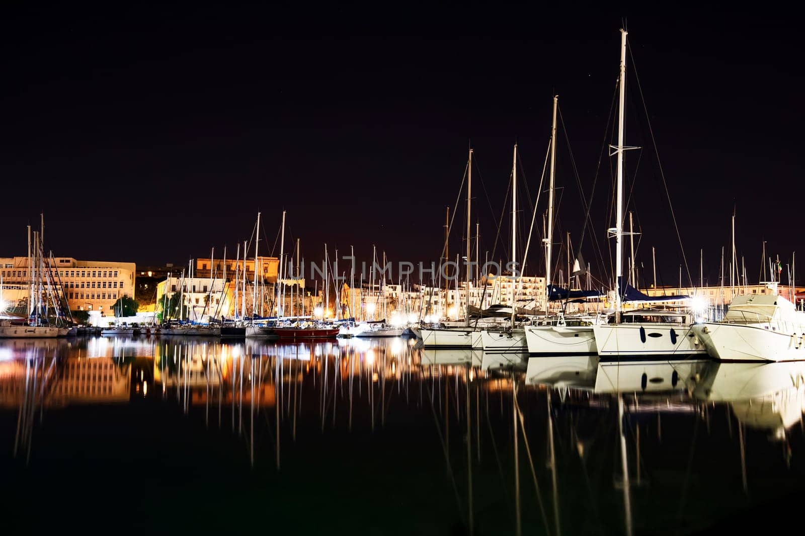 Moored boats and yachts at night in a harbor in Palermo, Sicily