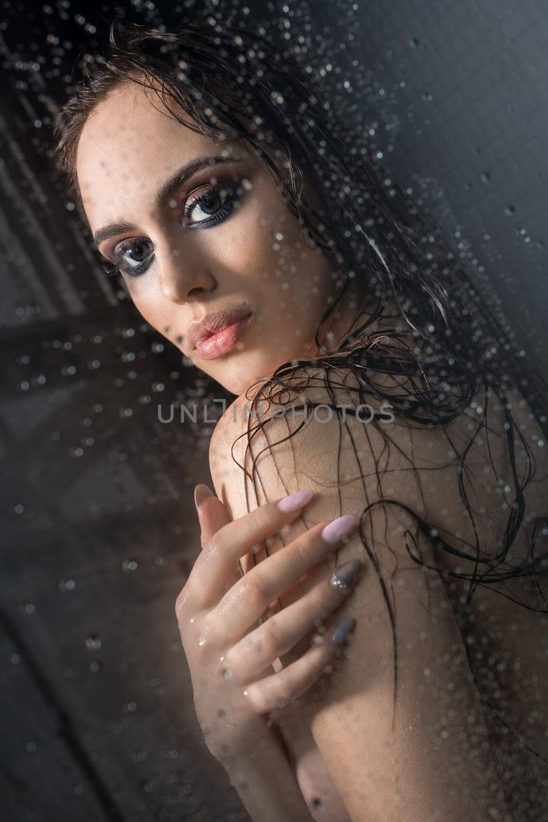 Nude beautiful brunette relaxing in shower her hair loose and wet