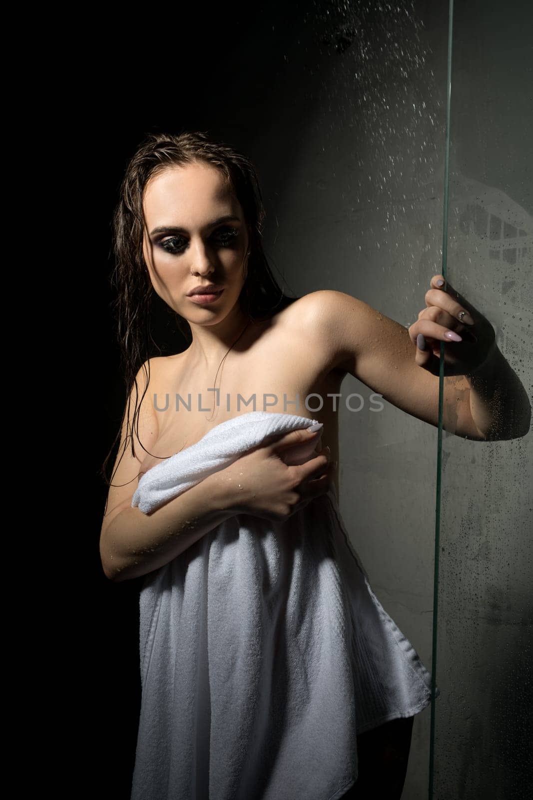 Gorgeous sexy brunette with smoky eyes wrapped in towel after shower