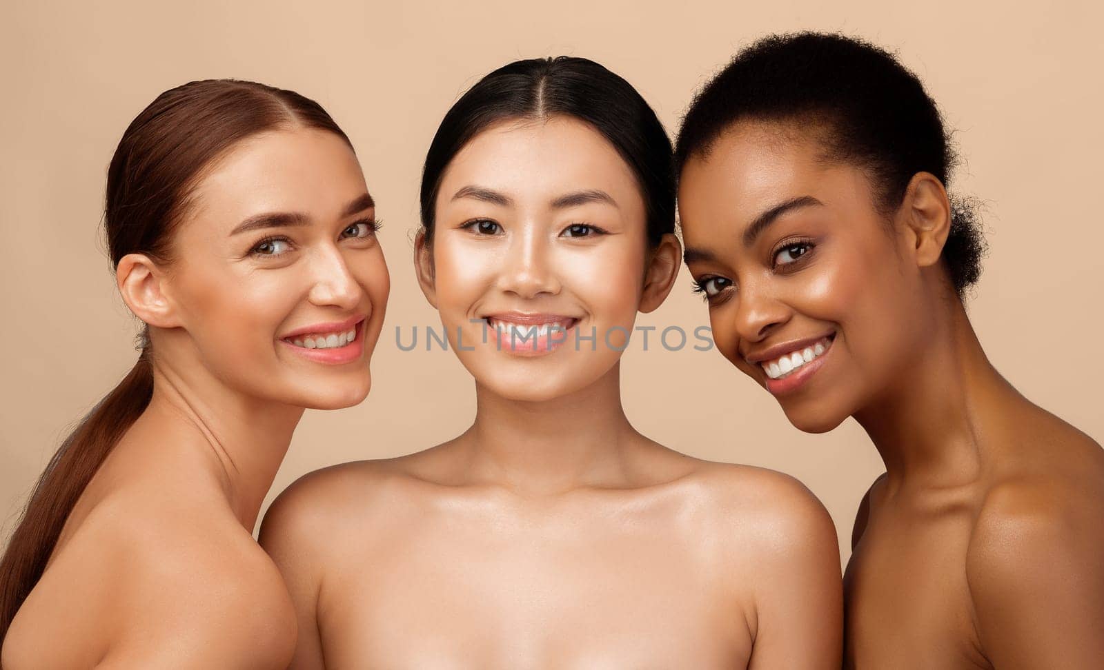 Three Gorgeous Girls Models Posing Naked Smiling To Camera Standing Over Gray Studio Background. Beauty And Body Care Concept