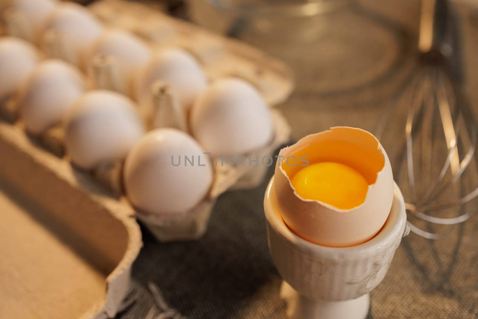 large broken chicken egg in a special container on the background of a box with eggs, concept of fresh organic eggs