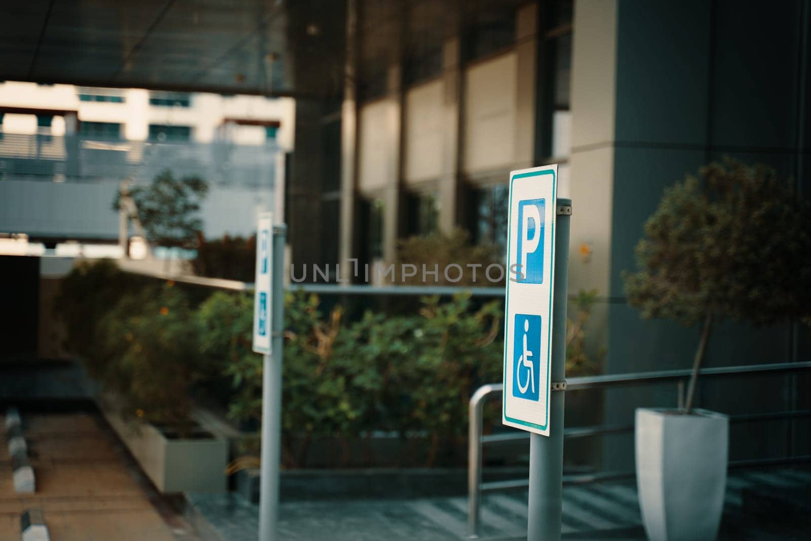 A parking sign with the letter P indicates parking available for building visitors. The facade of the building features glass windows and wooden doors
